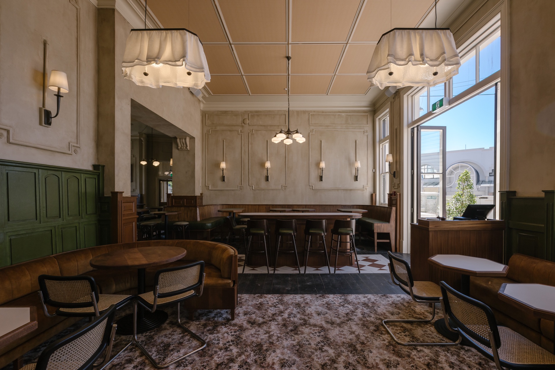 Hotel Ponsonby dining room, with a curved booth, green panelling and tall windows onto the street