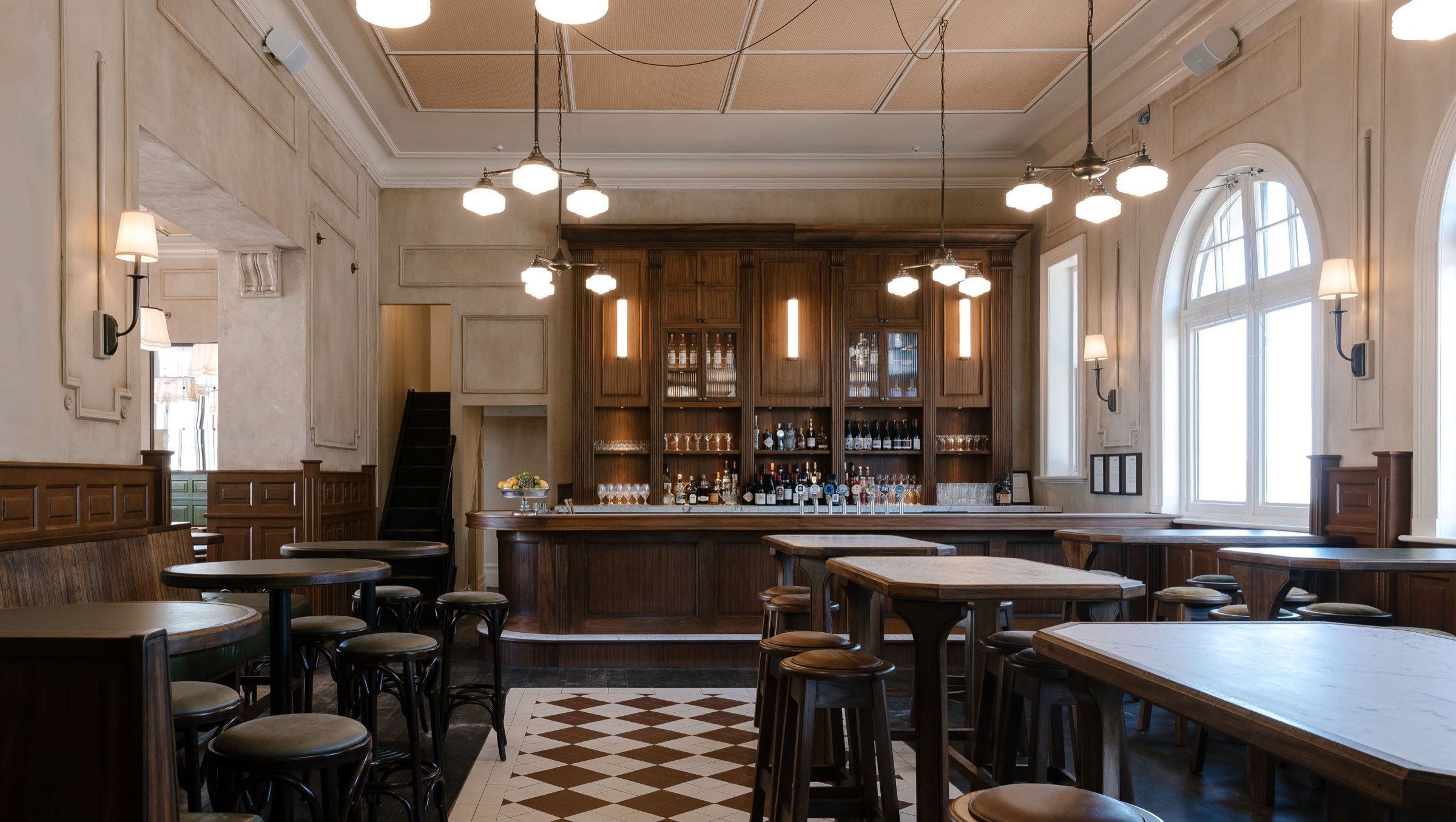 The public bar at Hotel Ponsonby, with its timber bar back, tiled floor and arched windows
